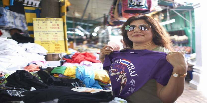 A lady choosing from a bunch of T-shirts to buy