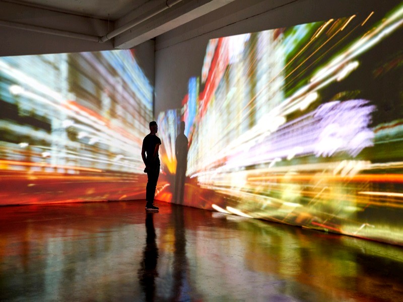 Man looking at abstract city scape being projected in a gallery space