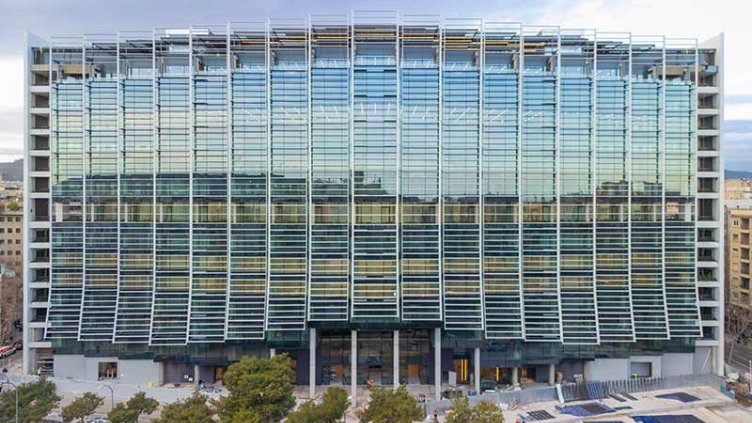 A tall building constructed of glass, characterized by its many large windows and reflective surfaces.