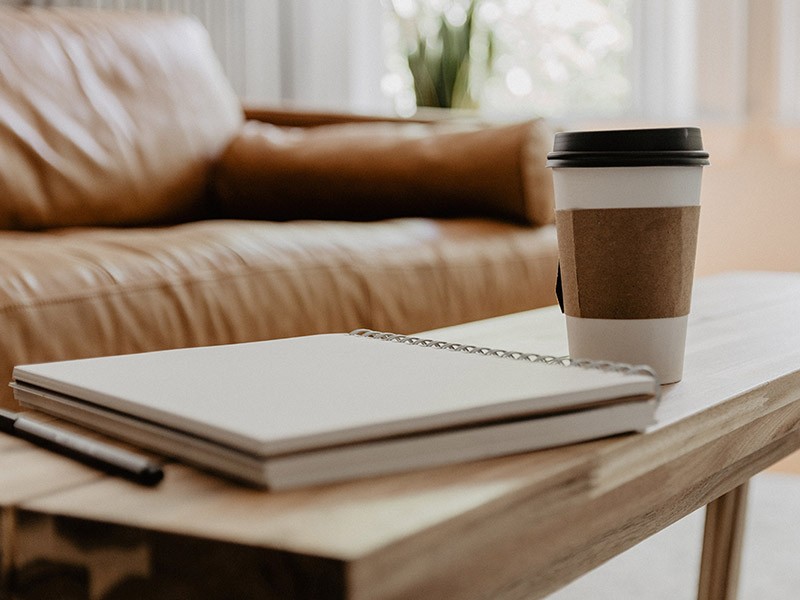 A table in front of sofa with a notebook and a mug