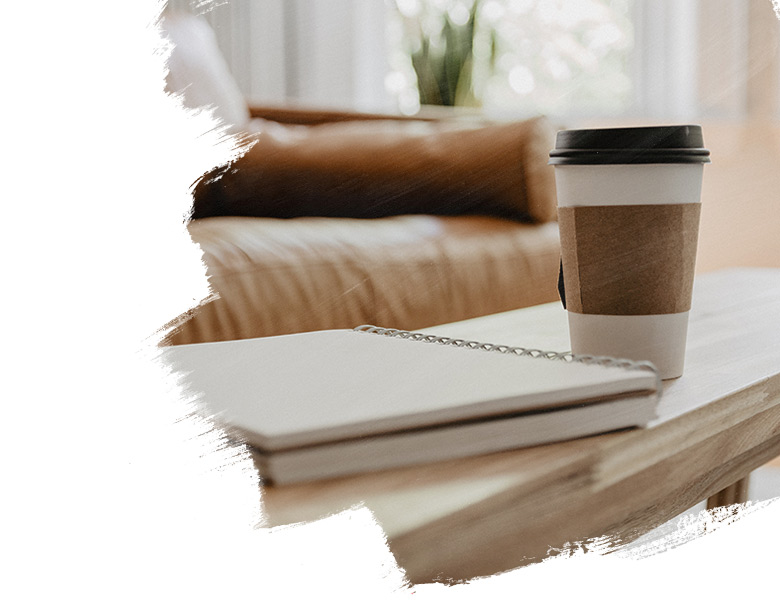 A table in front of sofa with a notebook and a mug