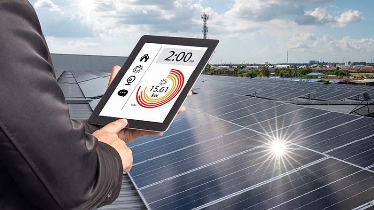 Man examining generation of solar power plant, holding digital tablet with a chart of electricity production.