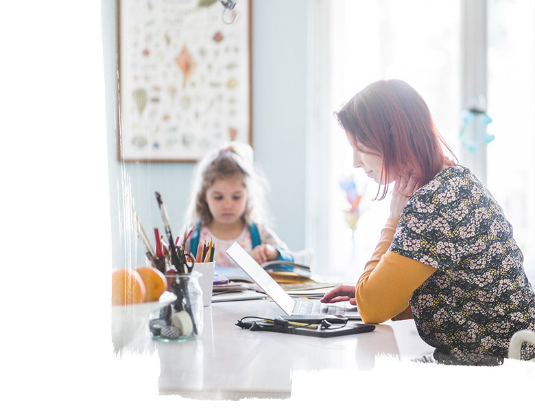 Side view of adult working on laptop while sitting with child at kitchen island